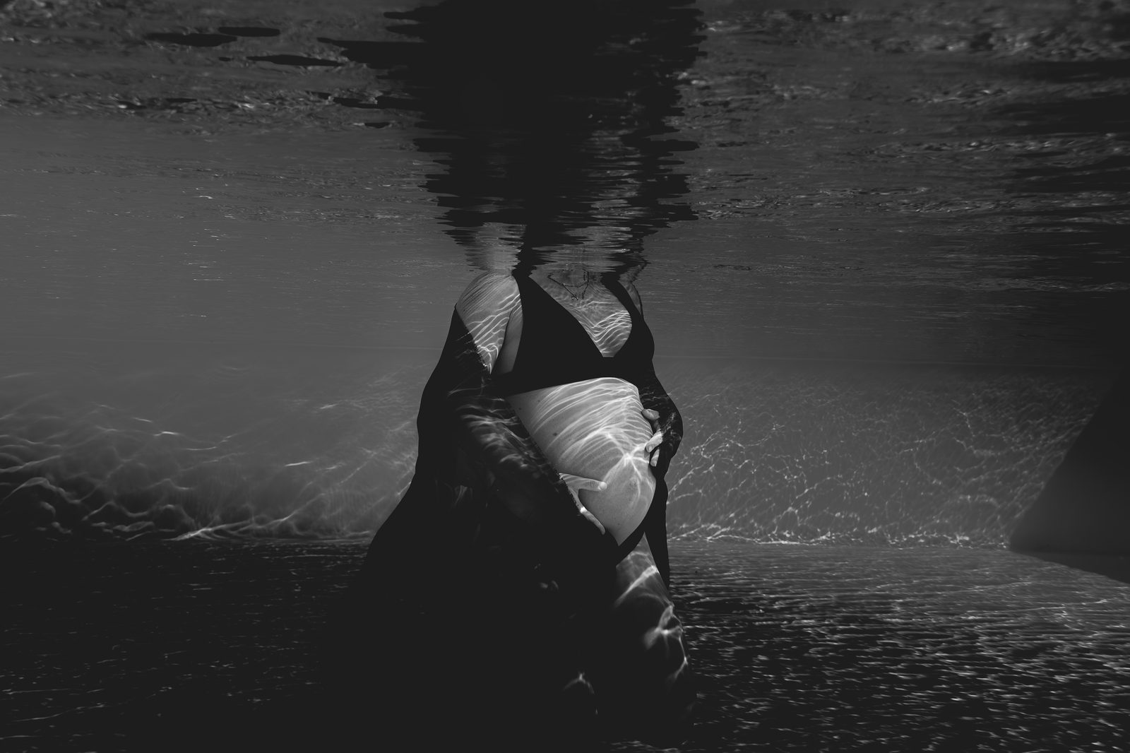 Future maman en apesanteur, lumière traversant la surface de la piscine