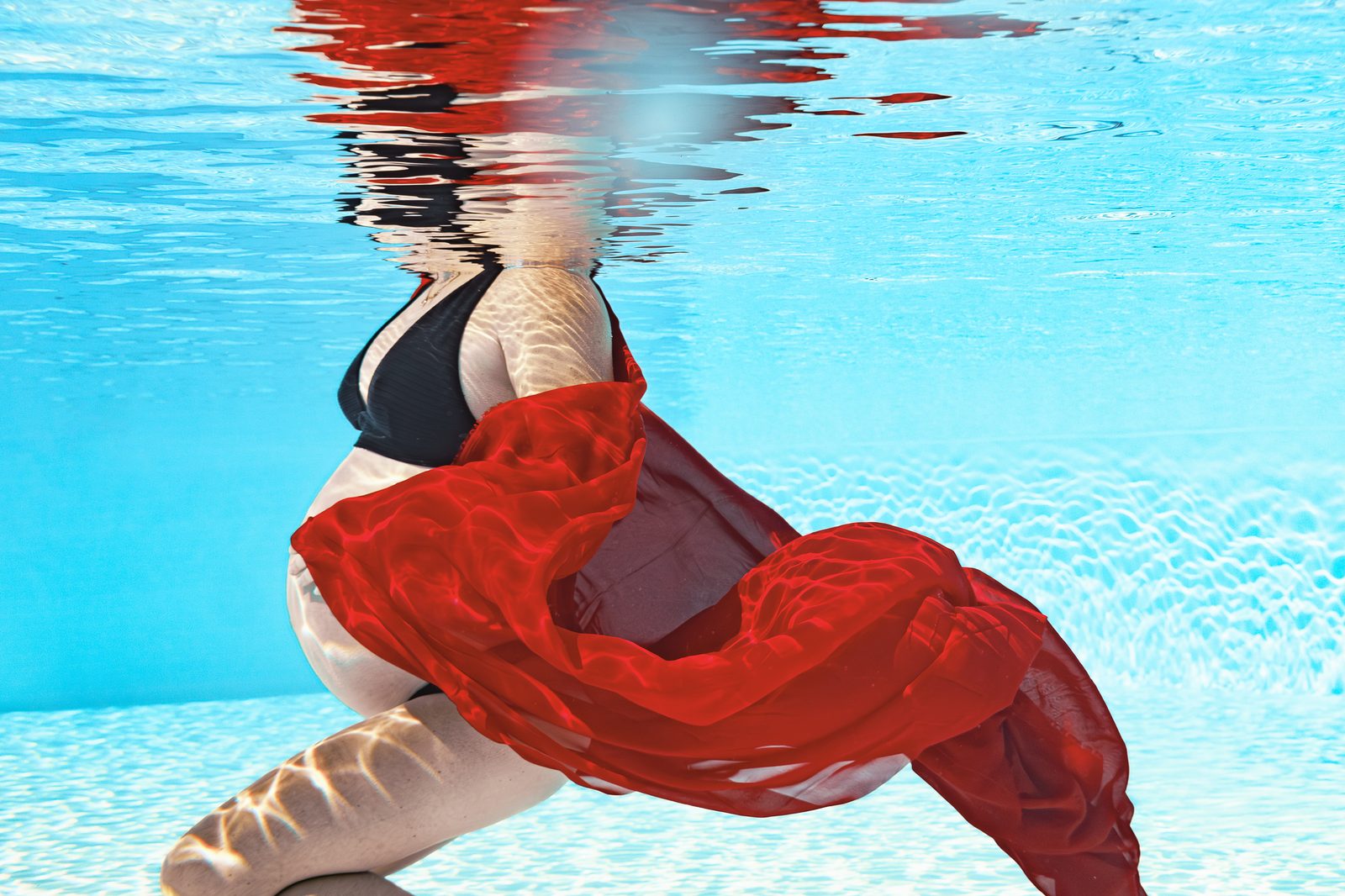 Future maman sous l'eau, voile rouge en apesanteur — photographie grossesse aquatique