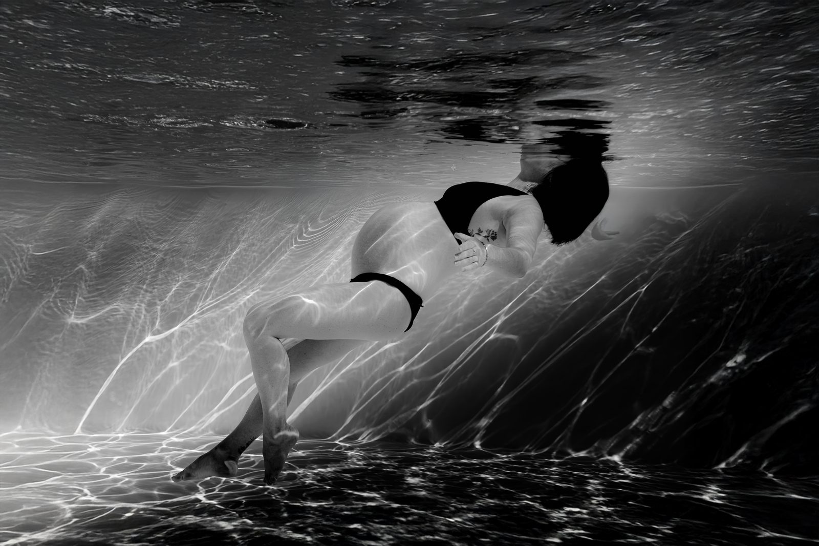 Portrait noir et blanc de femme enceinte sous l'eau